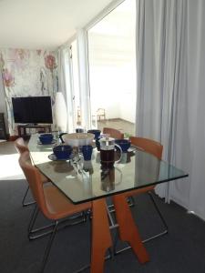 a glass table with chairs and a television in a room at Pool House in La Santa