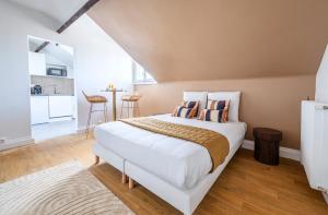 a bedroom with a large white bed and a kitchen at Studio confortable Anciennes écuries réhabilitée in Issy-les-Moulineaux