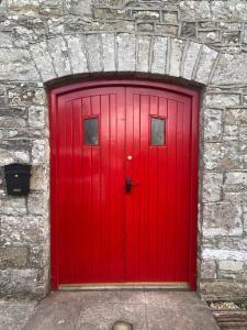 una porta rossa in un garage con parete in pietra di The Old Mill, Kilcorkey Bellanagare, Castlerea, County Roscommon - West of Ireland - House 2 a Bellanagare