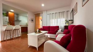 a living room with a red couch and a kitchen at Mika's House Valley in Sanlúcar de Barrameda