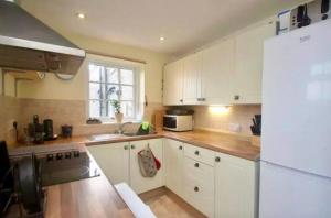 a kitchen with white cabinets and a white refrigerator at The White Cottage 3 stocks Green in Darley