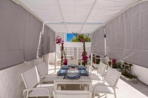 a table with white chairs and blue dishes on it at Villetta BiancAmare by BarbarHouse in Specchiolla 