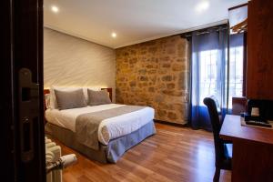 a bedroom with a bed and a brick wall at Hotel El Doncel in Sigüenza