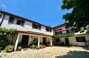 a large white building with flowers in a courtyard at Guest House Renata in Plomin