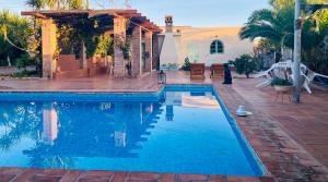 a swimming pool in front of a house at La Casita del Cactus - Casa de campo con piscina in Alcalá de Guadaira