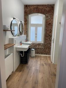 a bathroom with two sinks and a brick wall at Pension Klein und Fein in Heimbach
