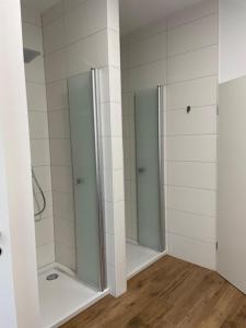 a bathroom with three walk in showers with white tiles at Pension Klein und Fein in Heimbach +20 photos