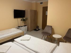 a room with two beds and a tv and a chair at VT6 House & Restaurant in Znojmo