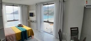 a bedroom with a large window with a view of the ocean at Loft da Prainha in Arraial do Cabo