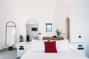 a bedroom with a white bed with a red pillow at Santonero in Akrotiri