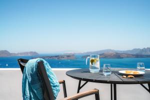 a table with a plate of food and glasses on a balcony at Santonero in Akrotiri