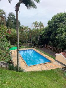 a swimming pool in a yard with a palm tree at Chácara casa da sogra in Santana de Parnaíba