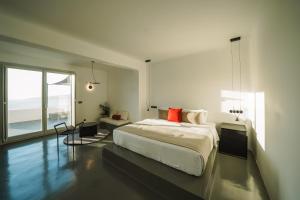 a white bedroom with a bed and a large window at Santonero in Akrotiri