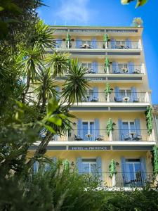 a hotel with palm trees in front of a building at Hôtel de Provence in Cannes
