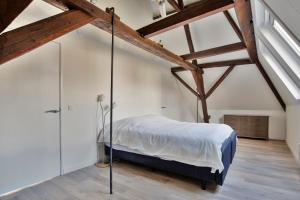 a bedroom with white walls and wooden beams at De Kleine Lantaarn in Bergen op Zoom