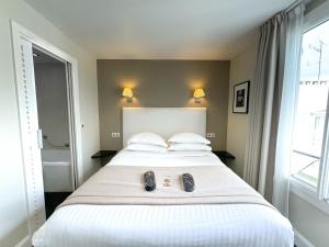 a bedroom with a large white bed with shoes on it at Hôtel de Provence in Cannes