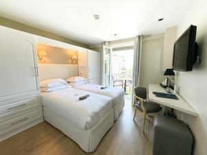 a bedroom with a bed and a desk and a television at Hôtel de Provence in Cannes