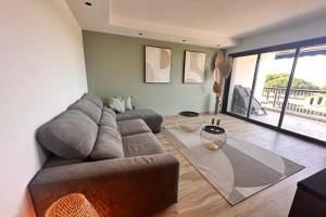 un salon avec un canapé et une grande fenêtre dans l'établissement Le Mistral Appartement Standing avec Vue Mer Exceptionnelle en 1ère Ligne, au Grau-du-Roi