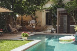 a swimming pool in a backyard with a table and chairs at La Domitia - Maison d'hôtes, massages & bien-être in Montbazin