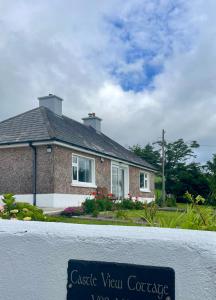 a house with a sign in front of it at Castle View Cottage - Entire Home in Ballynasare
