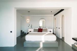 a white bedroom with a white bed with red pillows at Santonero in Akrotiri