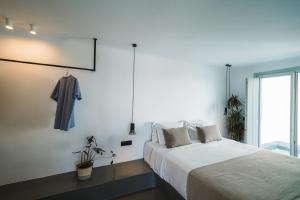a white bedroom with a bed and a window at Santonero in Akrotiri