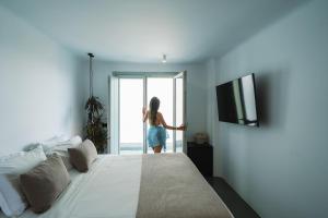 a woman standing in a bedroom looking out the window at Santonero in Akrotiri