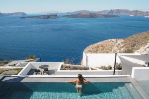 a woman in a swimming pool with a view of the ocean at Santonero in Akrotiri
