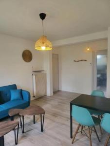 a living room with a blue couch and a table at Appartement Clermont-Ferrand F3 2 chambres 1 chambre avec 1 lit simple et 1 chambre avec 2 lits doubles in Clermont-Ferrand