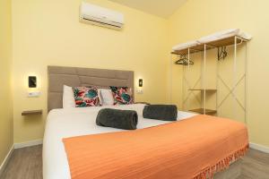 a bedroom with a large bed with an orange blanket at Florenças House - Private Jacuzzi & Garden in Calheta