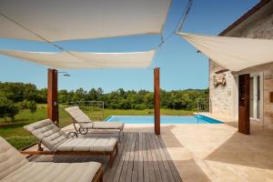 a patio with a white canopy and chairs and a pool at Rustic villa Krug with panorama view in Buje in Bibali