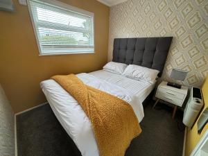 a bedroom with a bed with a blanket on it at 179, Two bed chalet on Sund0wner Holiday Park - Sleeps 4, free WiFi, sorry no pets - entertainment options close by in Hemsby