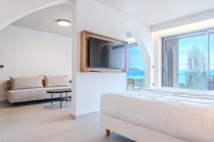 a white bedroom with a bed and a tv at Iolida Corfu Resort by Smile Hotels in Dassia +70 photos