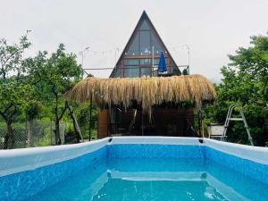 a house with a straw umbrella and a swimming pool at Mountain Star in Batumi