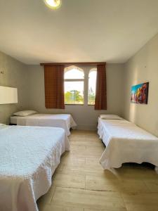 a room with three beds and a window at Pousada Areia da Praia in Fortaleza