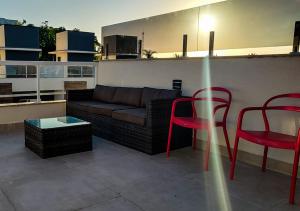 een woonkamer met een bank en 2 rode stoelen bij Serena Beach Triplex in Caraguatatuba +24 foto's