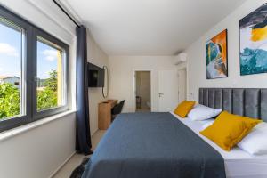 a bedroom with a bed with yellow pillows and a window at D Marine villa in Bibinje