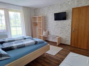 - une chambre avec 2 lits et une télévision sur un mur en briques dans l'établissement Ferienwohnungen Pollhammer, à Sankt Gallenkirch