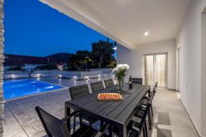 ein Esszimmer mit einem Tisch, Stühlen und einem Pool in der Unterkunft Villa Sea View - heated pool & 2 mins to the beach in Vinišće + 82 Fotos