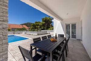 ein Esszimmer mit einem Tisch, Stühlen und einem Pool in der Unterkunft Villa Sea View - heated pool & 2 mins to the beach in Vinišće