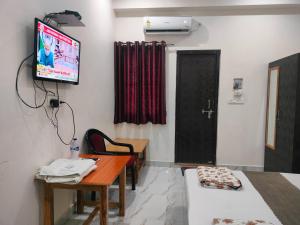 a room with a tv and a desk and a table at Hotel Dev Inn Ayodhya in Ayodhya
