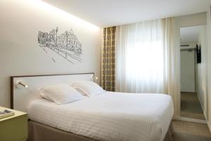 a bedroom with a white bed and a window at Hotel du Pin Nice Port by Soniho in Nice