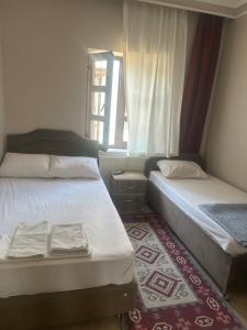 two beds in a small room with a window at ESER PALAS OTELİ in Konya
