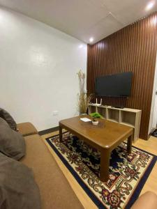 a living room with a coffee table and a tv at flores staycation in Marilao