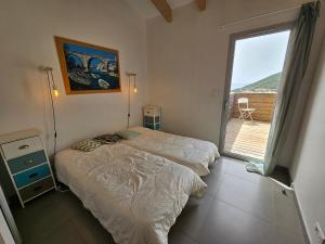 two beds in a room with a large window at SERENA-Piscine privée- Vue Mer in Conca