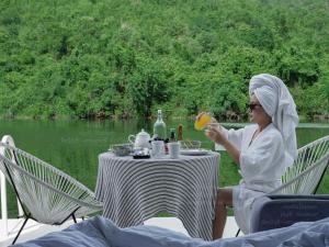 a woman sitting at a table with a drink at RaftDara Erawan Resort in Tha Kradan