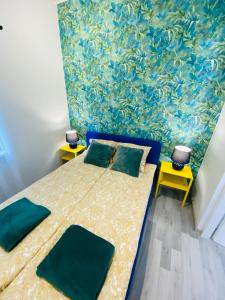 a bedroom with a bed with green pillows and a wallpaper at Apartamenty pod wieżą 2 in Olsztynek