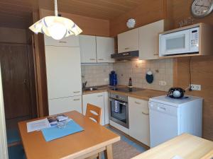 une cuisine avec des appareils électroménagers blancs et une table en bois avec une table dans l'établissement Ferienwohnungen Pollhammer, à Sankt Gallenkirch 52 autres photos