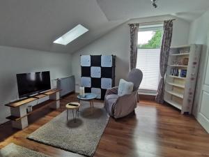 a living room with a tv and a chair and a table at Urlaub im Ruhrgebiet in Holzwickede