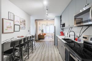 a kitchen with white cabinets and bar stools at Downtown Oasis-2BR-Spa Bath-Pet Friendly, Free Parking in Toronto